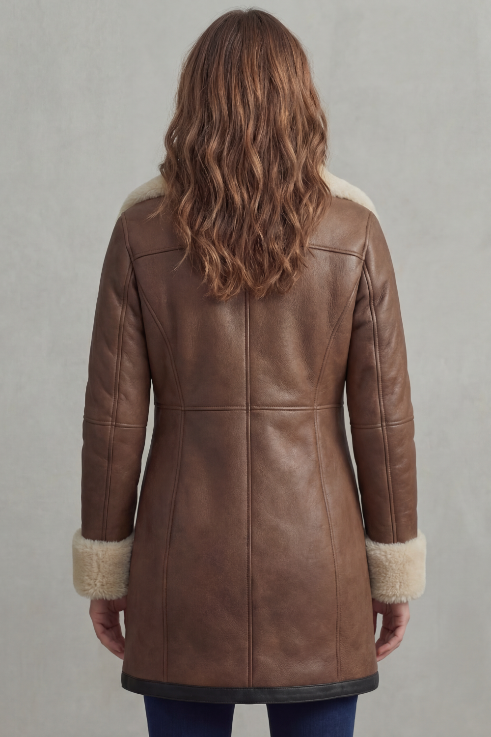 Brown leather winter coat back view with seam lines and shearling cuff trim