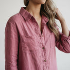 Pink linen jumpsuit close-up with button placket, V-neck collar, and chest patch pockets