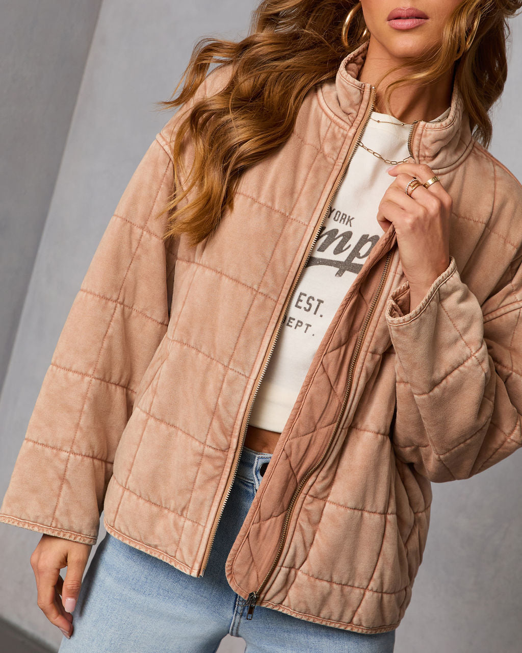 Close-up tan quilted zip jacket with stand collar, stitched panels, and ribbed cuffs