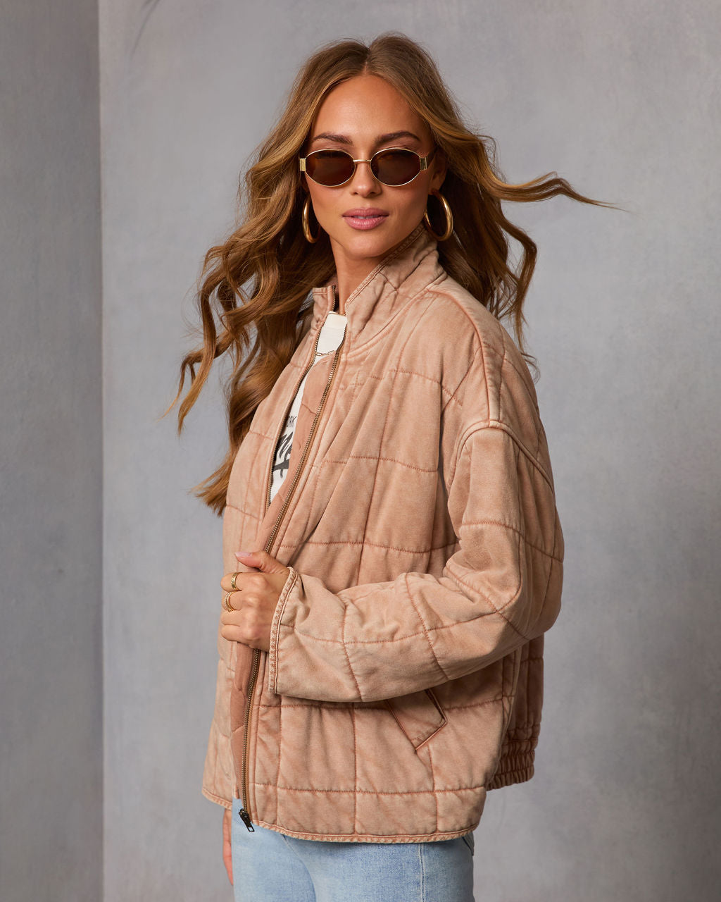 Tan quilted jacket with front zipper, stand collar, and long sleeves; stitched grid panels