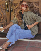 Olive quilted jacket with zip-front and long sleeves; model crouching side view.