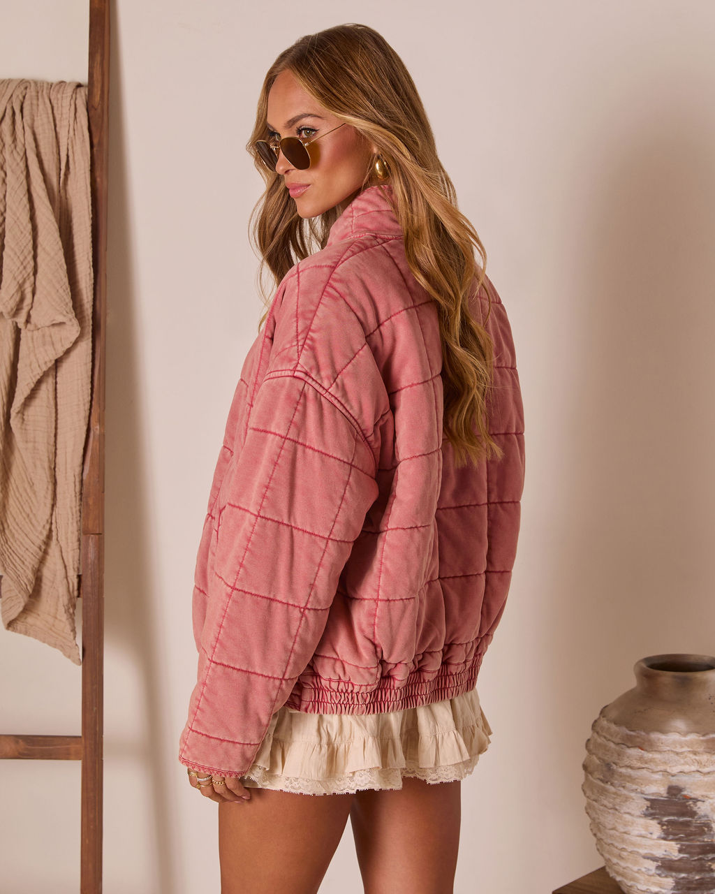 Side view of pink quilted zip jacket with long sleeves and elastic hem detail