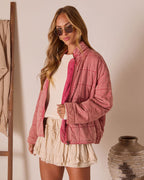 Pink quilted jacket with zipper front, stand collar, and long sleeves; stitched grid panels