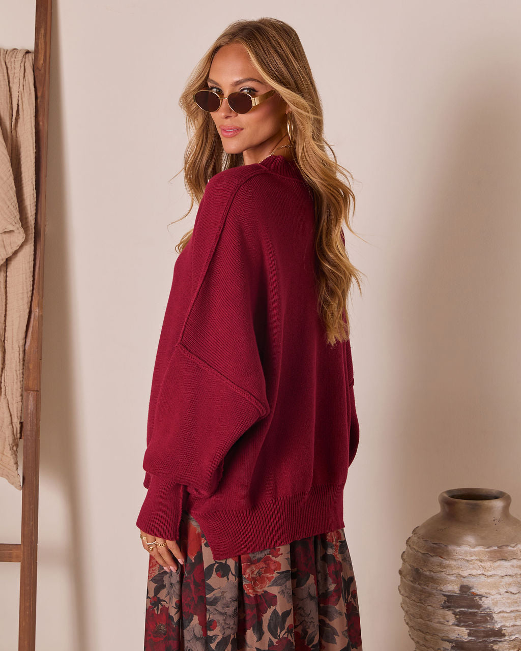 Oversized knit pullover sweater in deep red, side view with long sleeves and ribbing