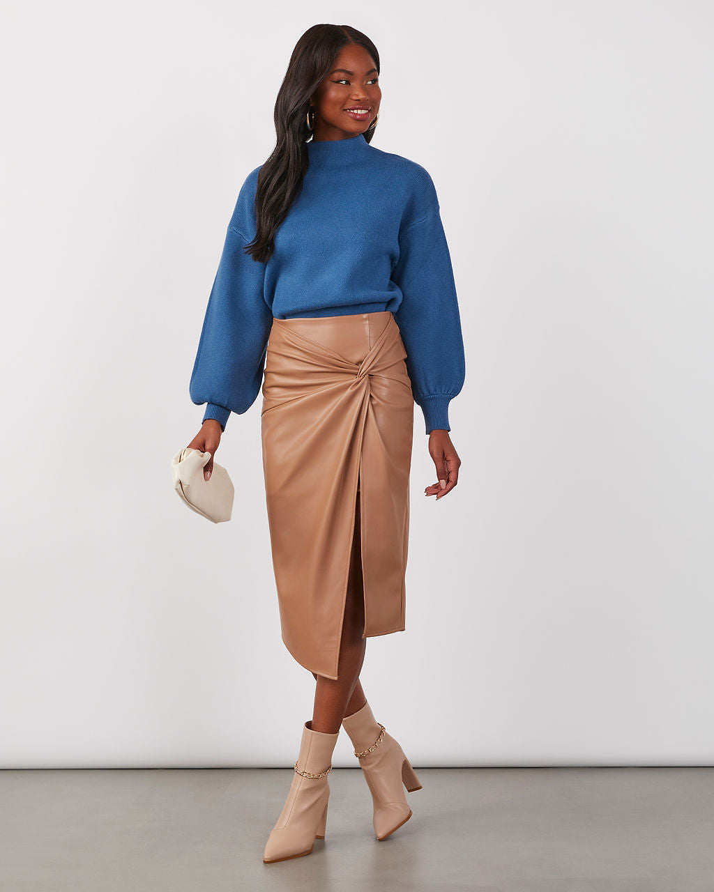 Blue mock neck knit sweater with balloon sleeves, worn with a tan ruched midi skirt.