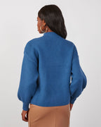 Blue mock neck sweater shown from back, with long sleeves and relaxed cropped hem.