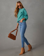 Mock neck sweater in teal, 3/4 side view with ribbed cuffs and hem over jeans