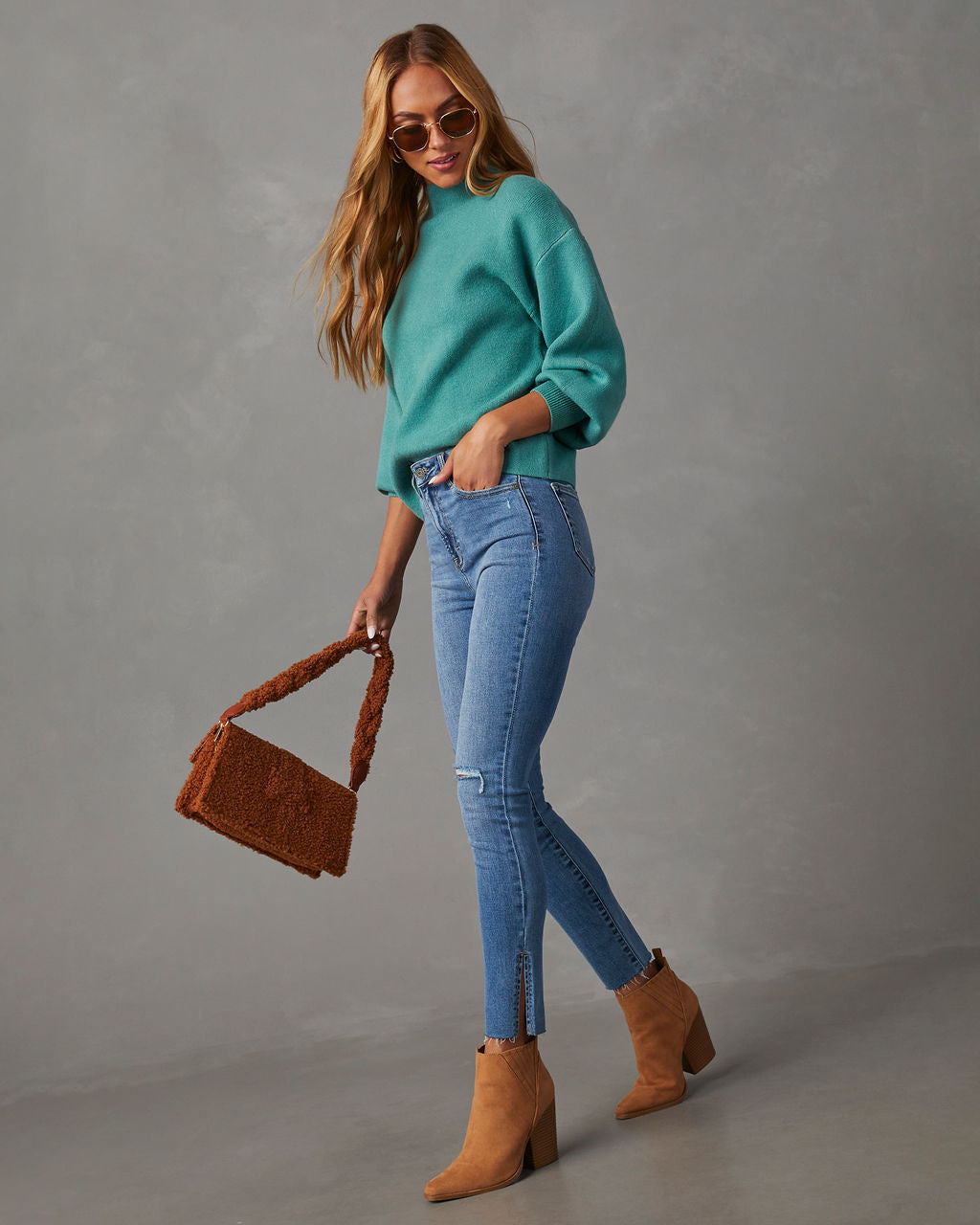 Mock neck sweater in teal, 3/4 side view with ribbed cuffs and hem over jeans