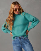 Mock neck sweater in teal, long sleeves and relaxed fit, paired with blue jeans