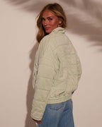 Light green quilted jacket with stand collar and stitched quilt panels on the back.