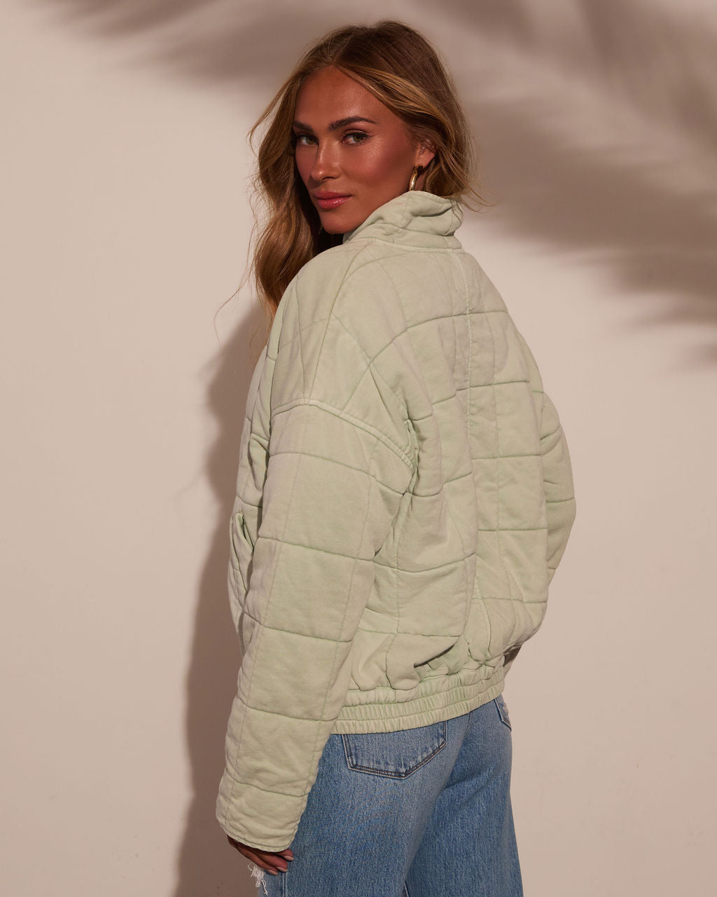 Light green quilted jacket with stand collar and stitched quilt panels on the back.