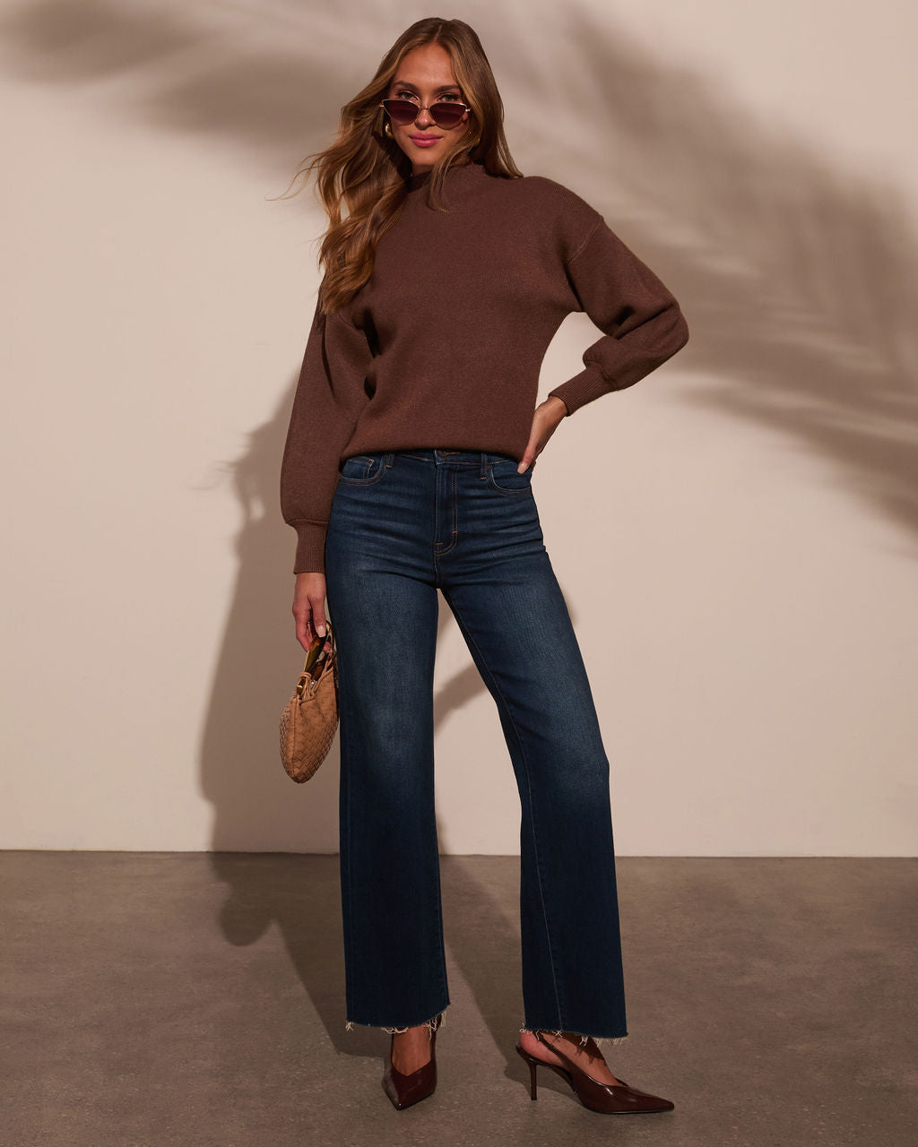 Mock neck sweater in dark brown, long sleeves with relaxed fit over blue jeans