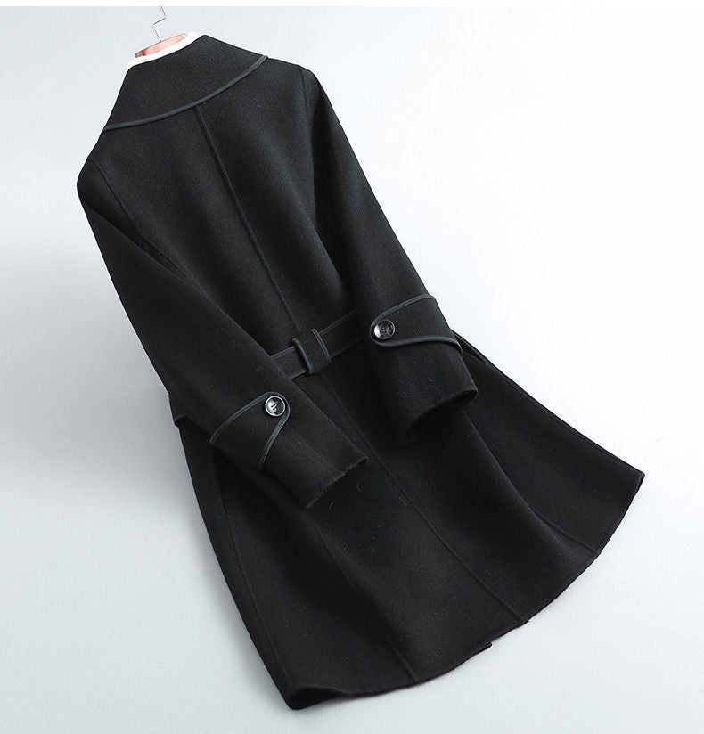 Black overcoat with wide lapels, belt tie, and round button accents