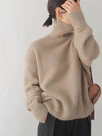 Beige turtleneck knit sweater with ribbed neckline and long sleeves with cuffs.