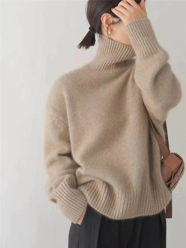 Beige turtleneck knit sweater with ribbed neckline and long sleeves with cuffs.