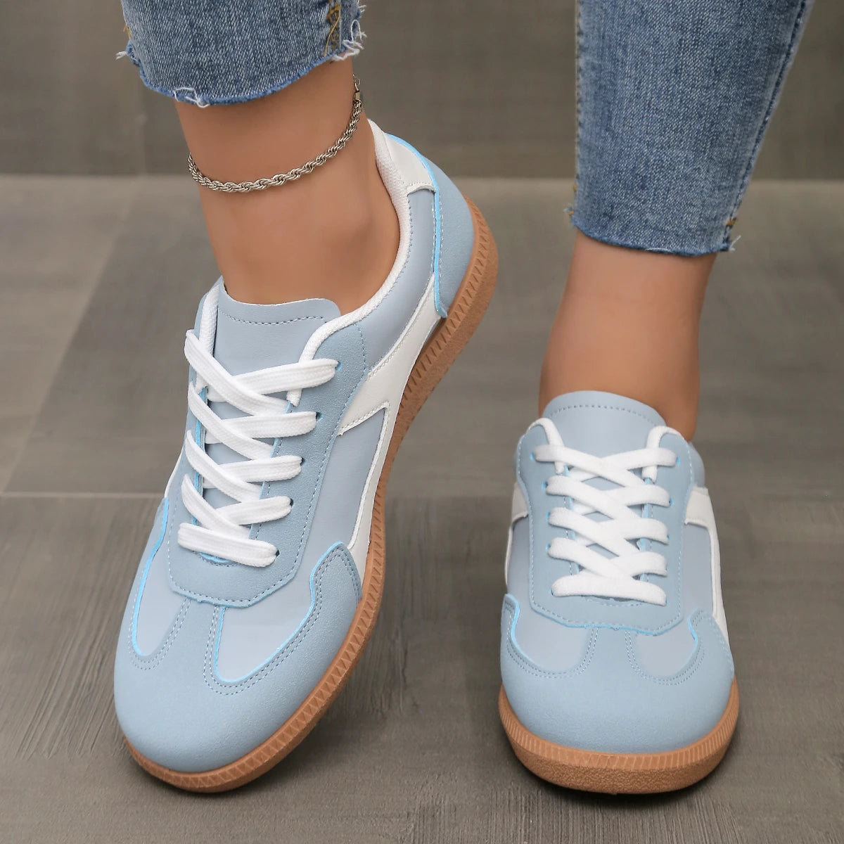 Light blue and white low-top sneakers with lace-up closure and gum sole