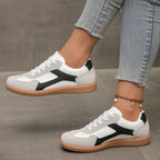 White sneakers with black side stripe, lace-up front, and gum sole