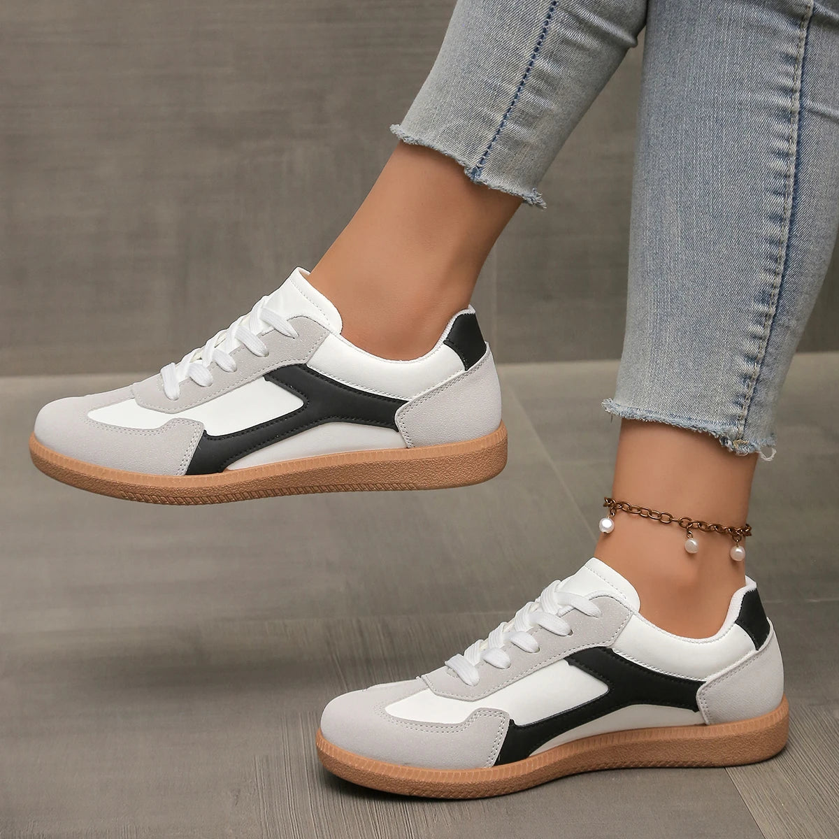 White sneakers with black side stripe, lace-up front, and gum sole