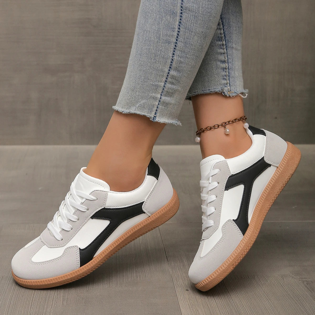 White and black low-top sneakers with lace-up front and gum sole