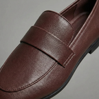 Dark brown leather loafer close-up with strap seam and textured upper