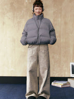 Gray short puffer jacket with full zip and stand collar, paired with wide-leg pants