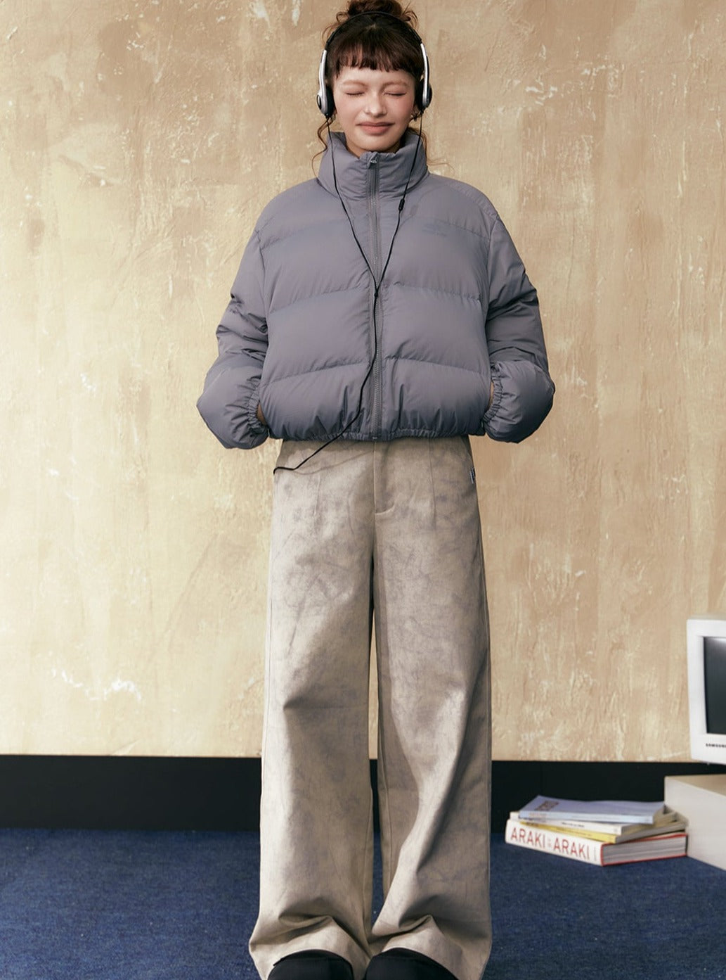 Gray short puffer jacket with full zip and stand collar, paired with wide-leg pants