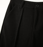 Black high-waisted wool-blend trousers with pleated front, belt loops, and button