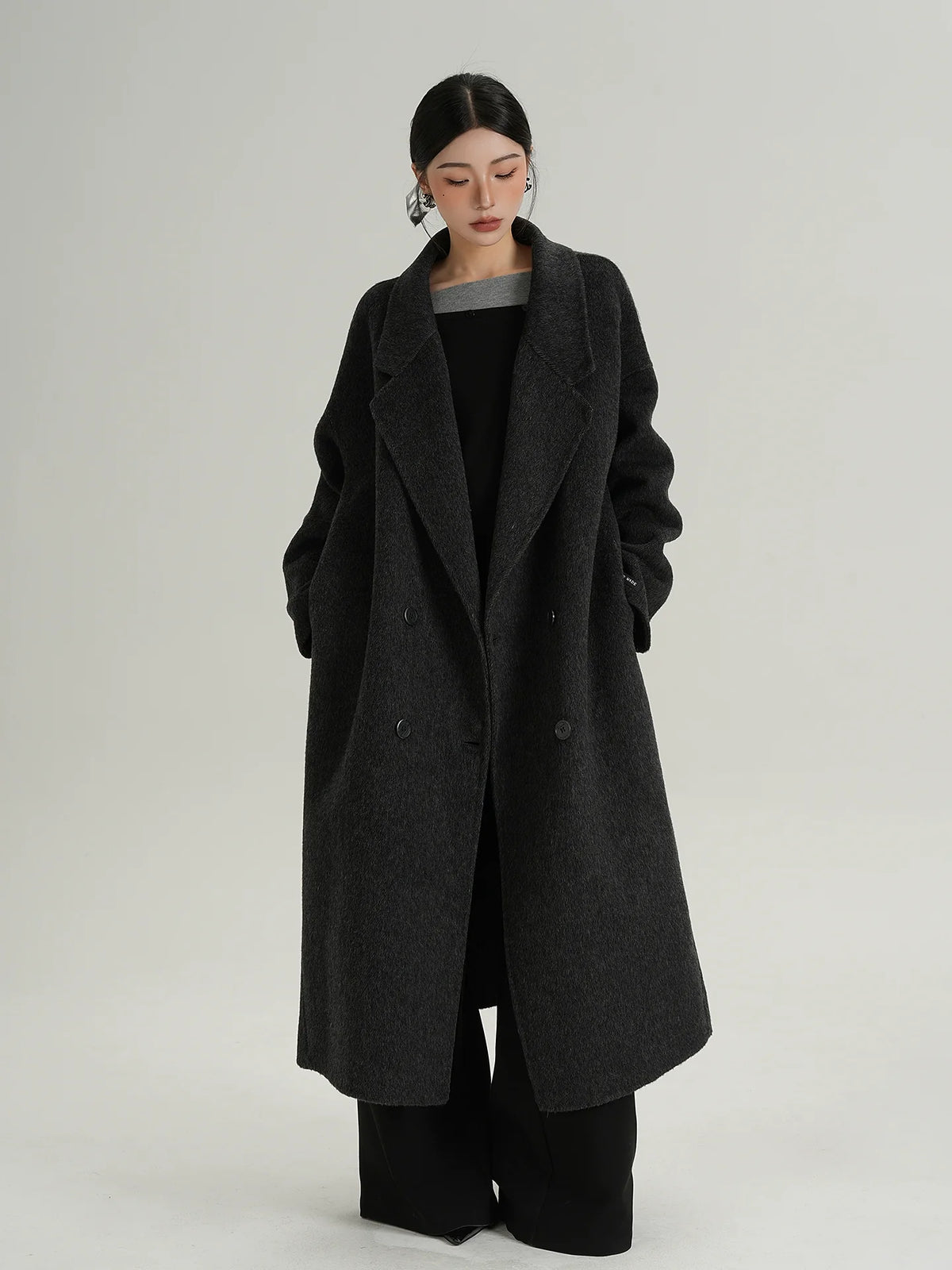 Long black double-breasted wool coat with notch lapels and button front, side view
