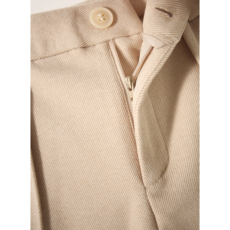 Close-up of beige wool-blend trouser front: button closure and zipper fly
