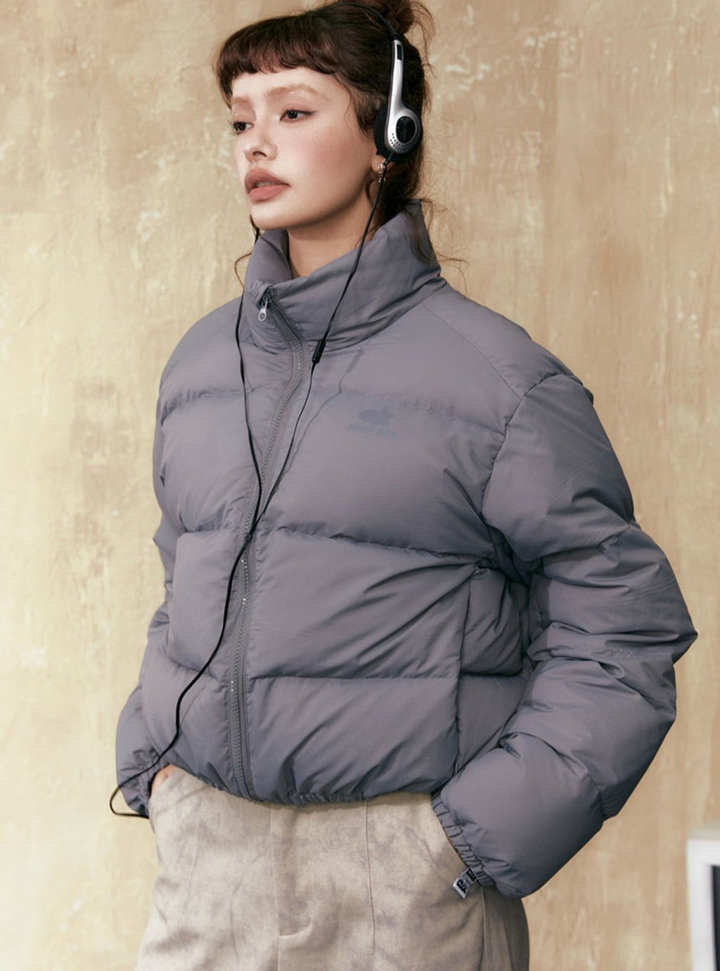 Gray short puffer jacket with stand collar, full-zip front, and quilted paneling