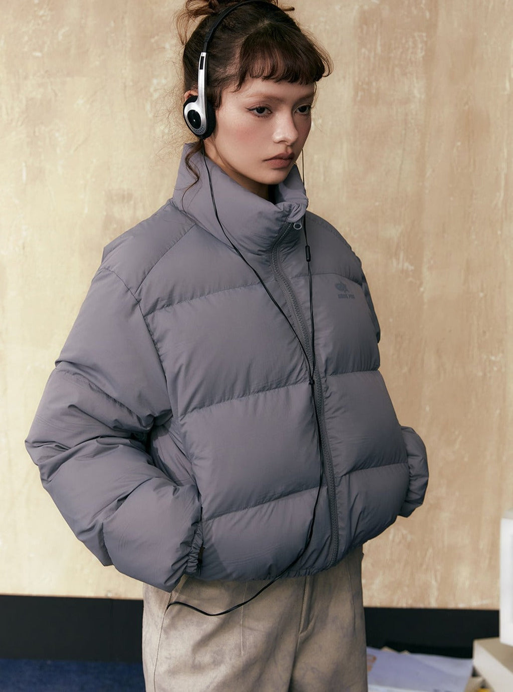 Gray short puffer jacket with full-zip front, stand collar, and side pockets