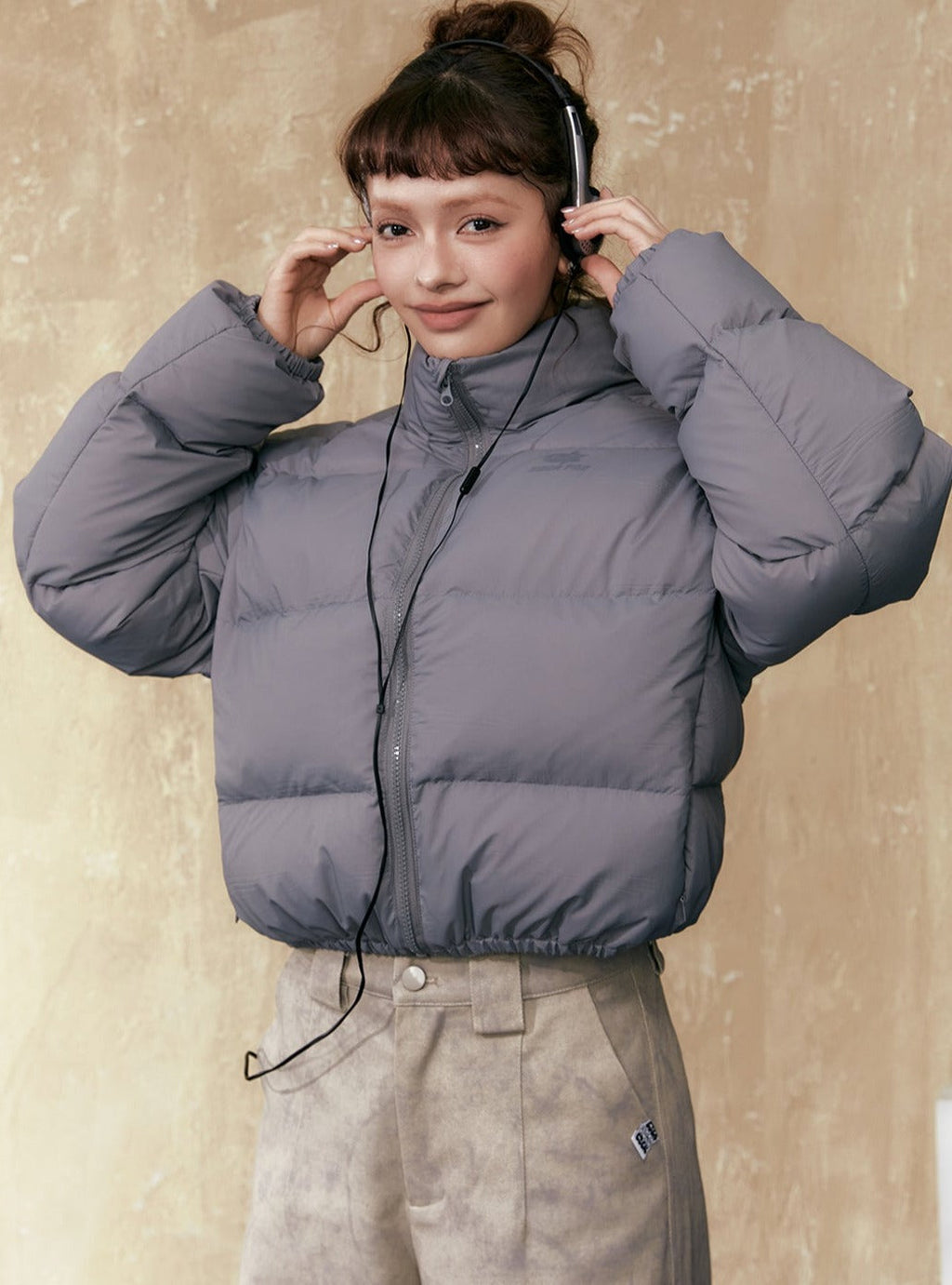 Gray short puffer jacket with full-zip front, stand collar, and drawstring hem