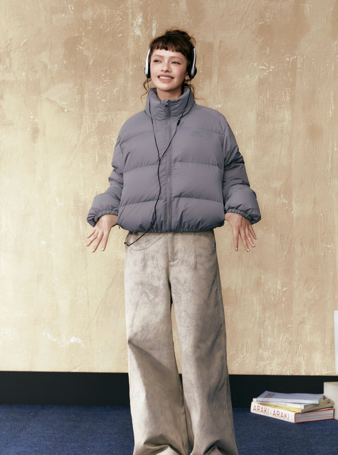 Gray short puffer jacket with full zip and stand collar, paired with wide-leg pants