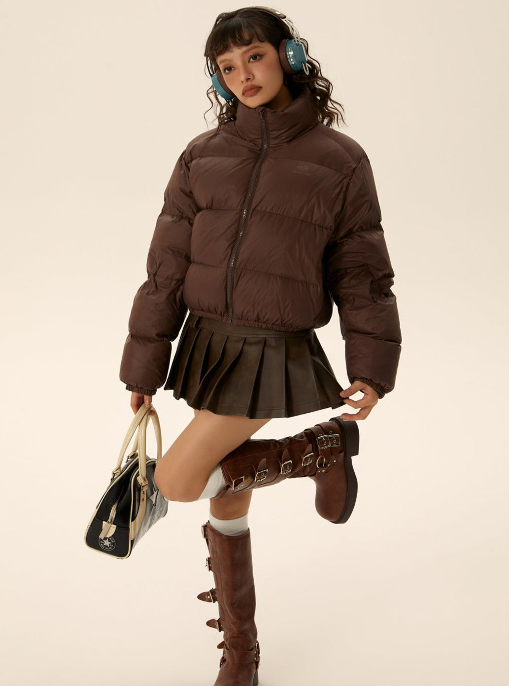 Brown short puffer jacket with zip front and elastic cuffs, styled with pleated skirt