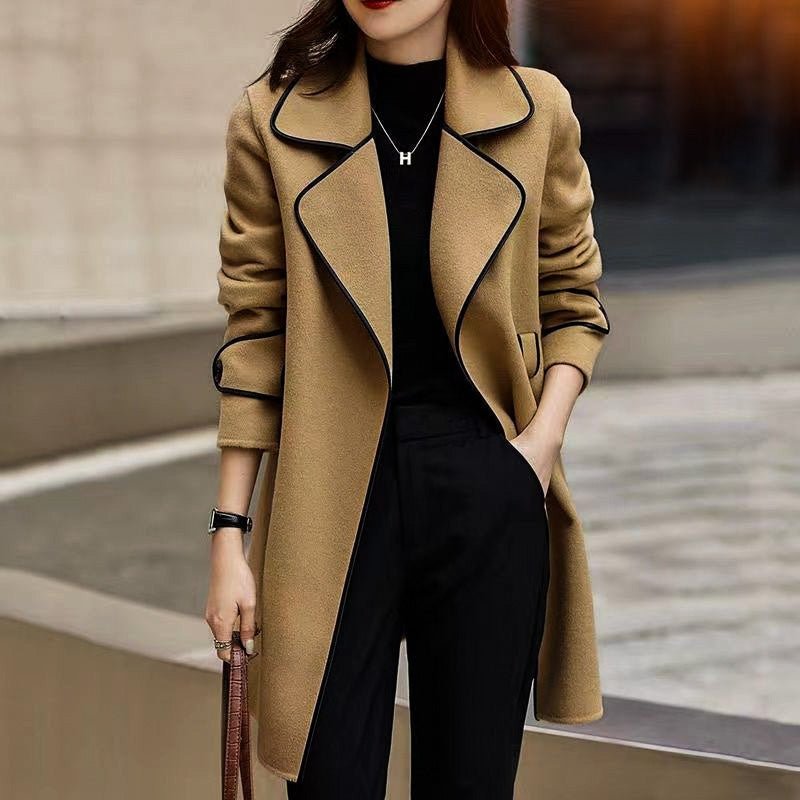 Beige wool coat with black-trim lapels and tie belt, worn open over a top