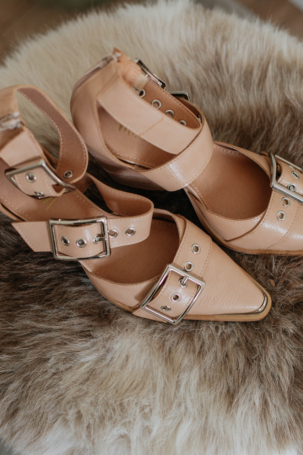 Beige heeled sandals with open toe, crisscross straps, and silver buckles