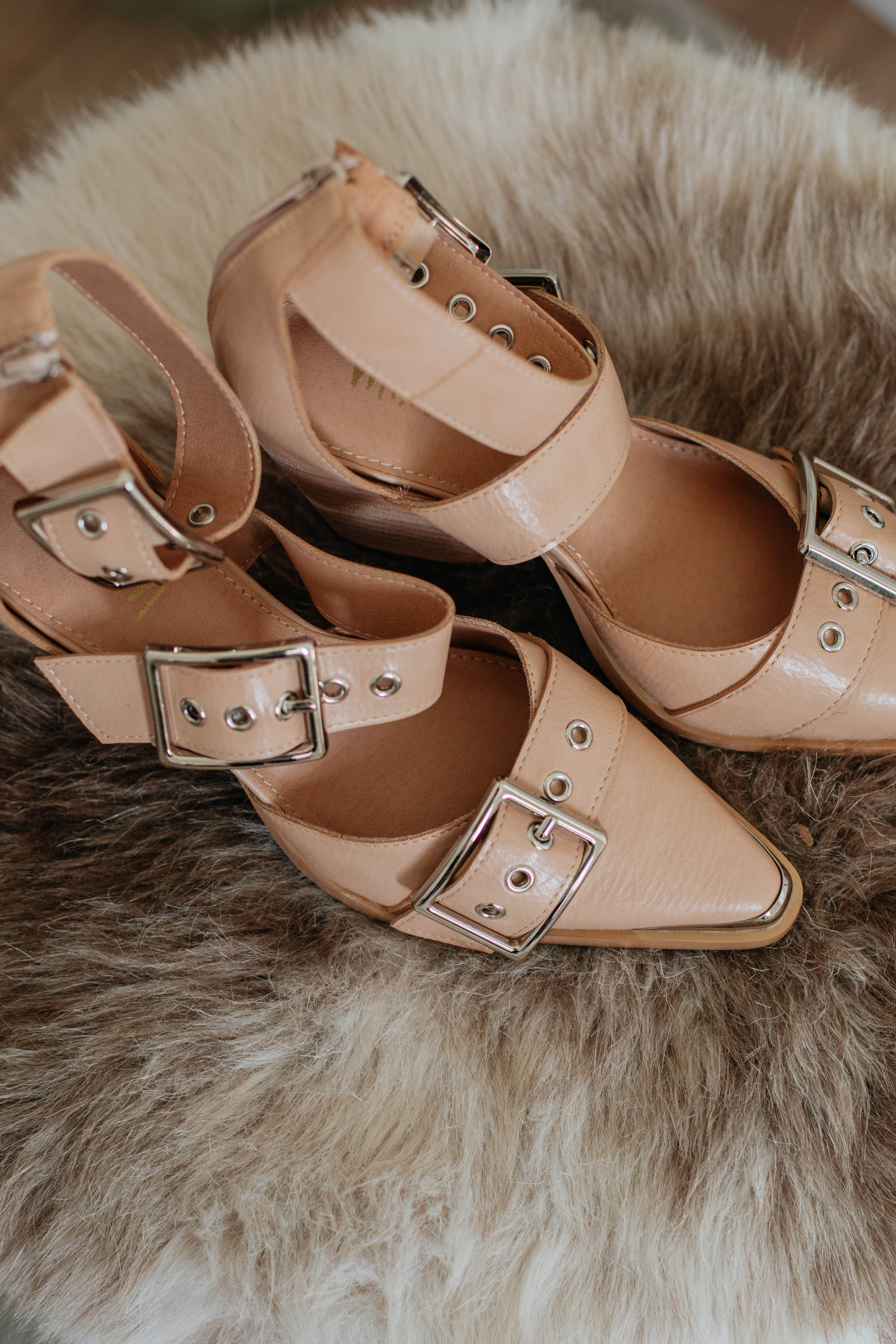 Beige heeled sandals with open toe, crisscross straps, and silver buckles