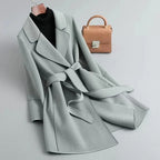 Light gray overcoat with wide lapels, belted waist, and cuff button detail