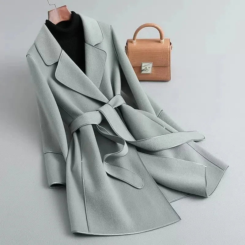 Light gray overcoat with wide lapels, belted waist, and cuff button detail