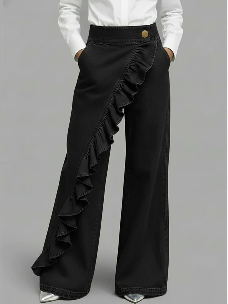 Black wide-leg jeans with diagonal ruffle overlay and gold button waistband