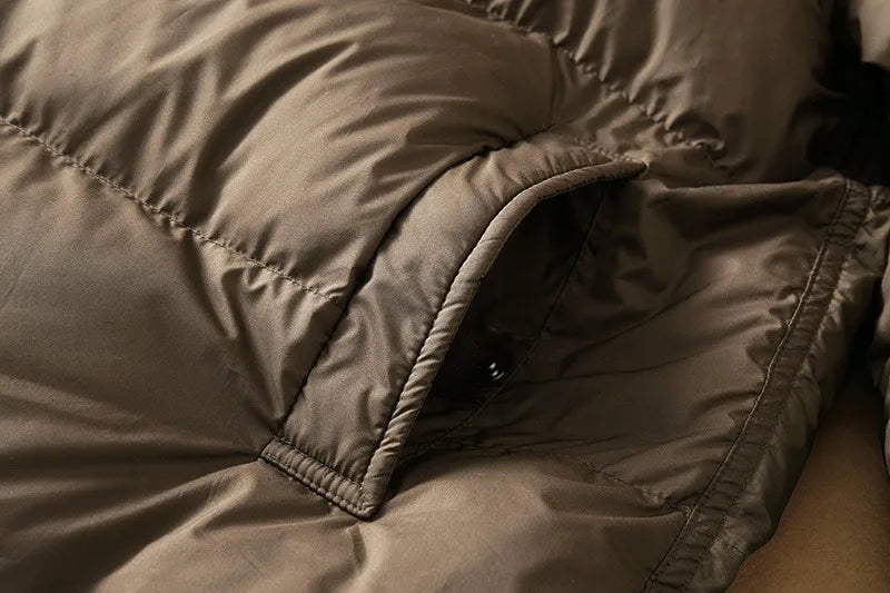 Long down puffer parka with quilted panels, zipper seam, and hood edge visible