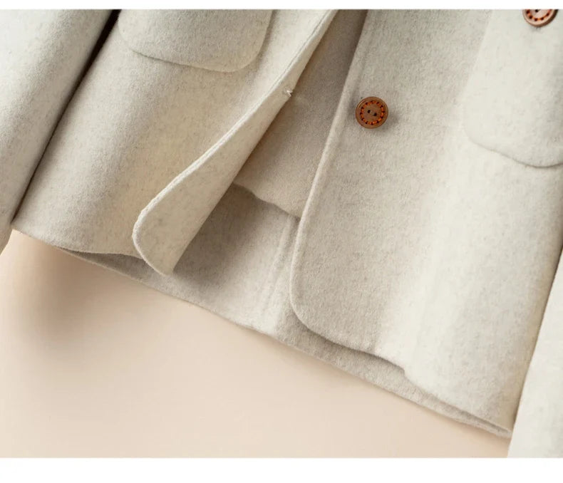 Ivory jacket close-up of patch pockets and button placket detail.