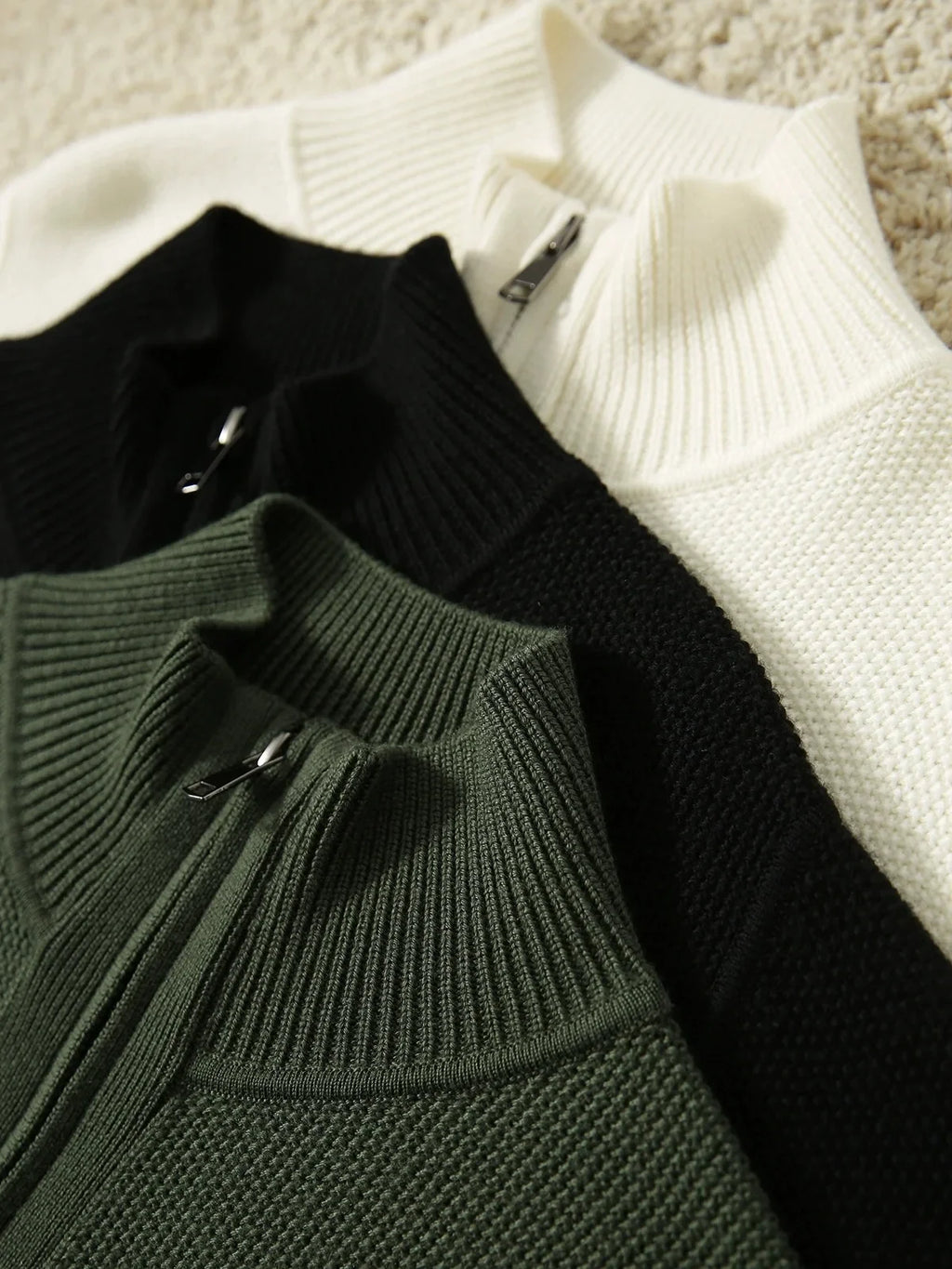 Zip-up knit cardigans in black, ivory, and dark green with front zippers.