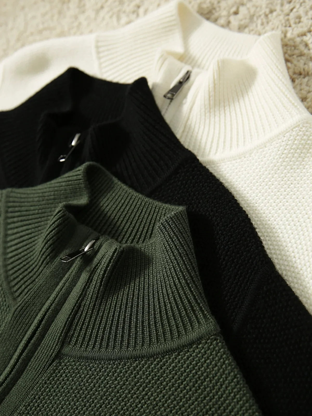 Zip-up knit cardigans in black, ivory, and dark green with front zippers.