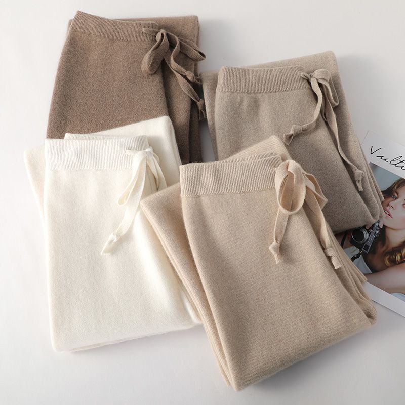 Folded women’s high-waisted lounge pants in white and taupe tones, each with drawstring