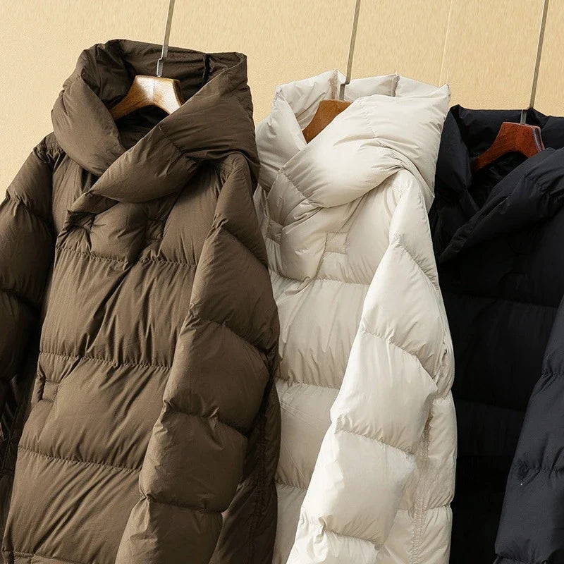 Coffee, white, and black down puffer parkas with hoods on hangers
