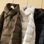 Coffee, white, and black down puffer parkas with hoods on hangers