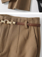 Tan trousers waistband close-up with chain-style belt and textured fabric