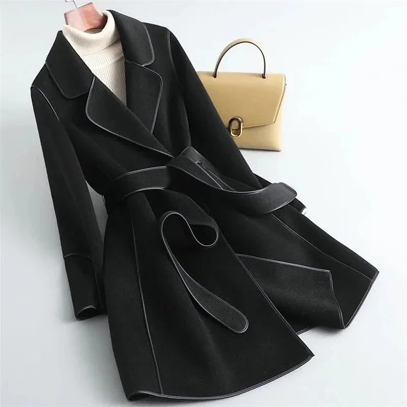 Black overcoat with notch lapels, belt tie, and flap pockets; structured seams.
