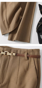 Tan wide-leg trousers close-up with draped front pleats and chain belt buckle